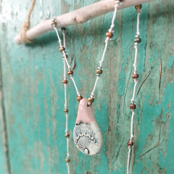 Collana in ceramica con motivo pressato rustico infilata su perle