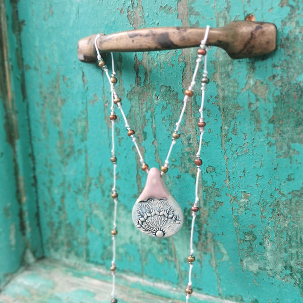 Collana in ceramica con motivo pressato rustico infilata su perle
